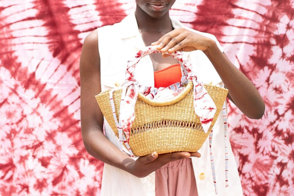 Woman holding a woven basket against a tie-dye background