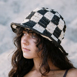 Woman wearing a checkered hat with a blurred natural background