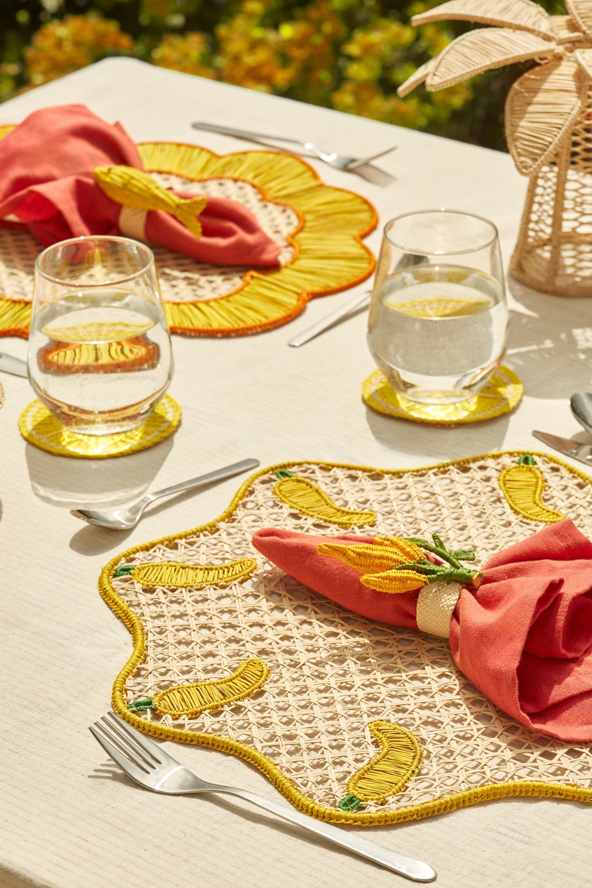 Table setting with decorative placemats, glasses, and cutlery on a light surface.