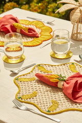 Table setting with decorative placemats, glasses, and cutlery on a light surface.