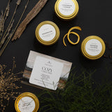 Collection of candles with gold lids on a dark surface with decorative elements.