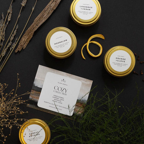 Collection of candles with gold lids on a dark surface with decorative elements.