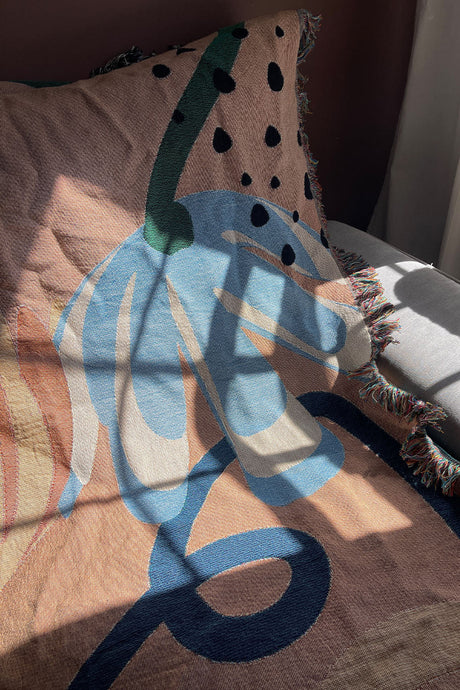 Abstract Garden Pink Cotton Woven Throw Blanket with a vibrant flower abstract design and fringe edges.