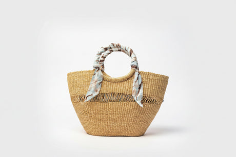 Woven straw bag with floral handle on a white background