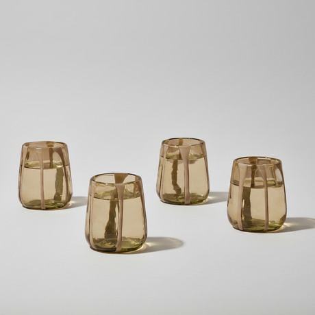 Four brown glass tumblers on a light gray background