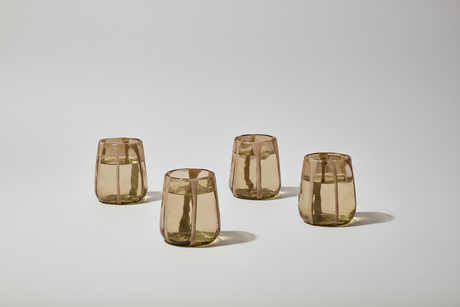 Four transparent brown glass tumblers on a light gray background