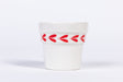White ceramic espresso cup with red leaf pattern on a white background