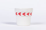 White ceramic espresso cup with red leaf pattern on a white background
