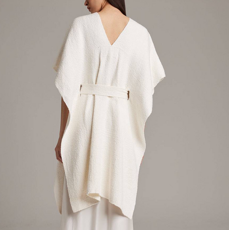 White textured dress with a belt on a plain background