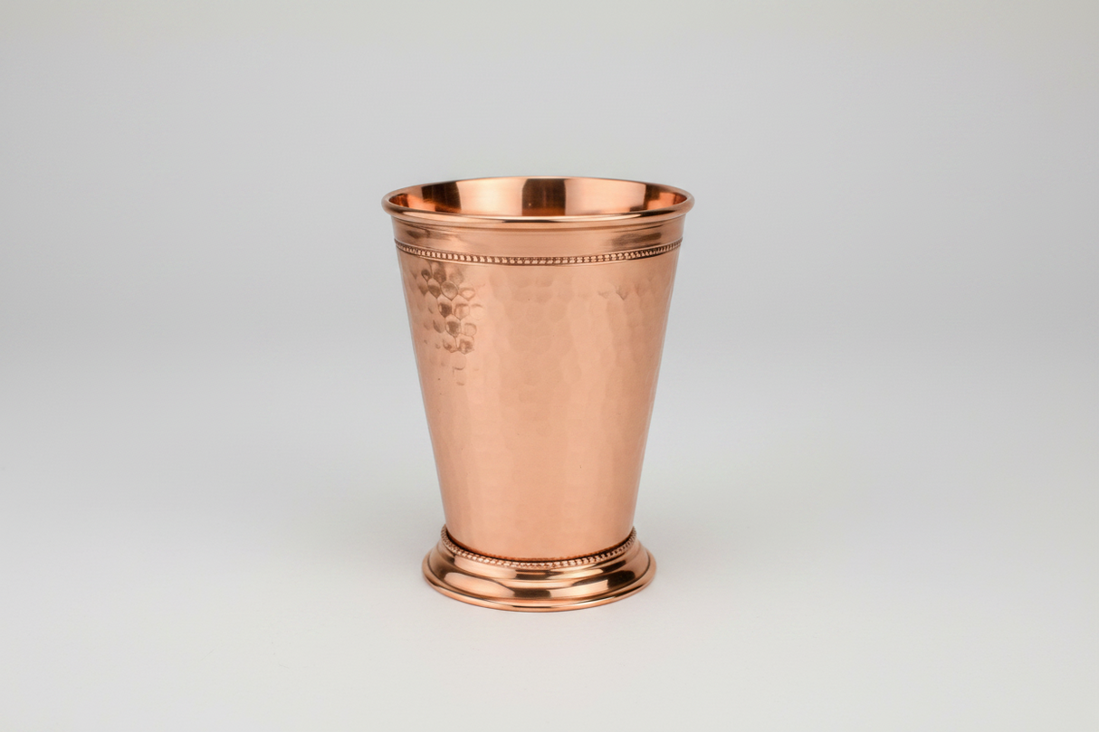 Copper mint julep cup on a light gray background