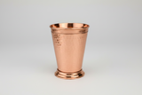 Copper mint julep cup on a light gray background