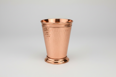 Copper mint julep cup on a light gray background