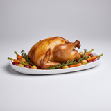 Roasted turkey on a platter with vegetables on a light gray background