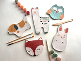 Set of children's ceramic animal plates with paintbrushes and paint on a light background