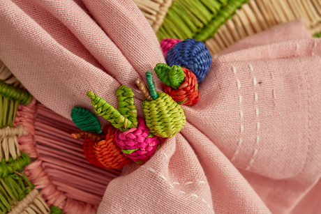 Close-up of a pink fabric with embroidered colorful vegetables on a textured background