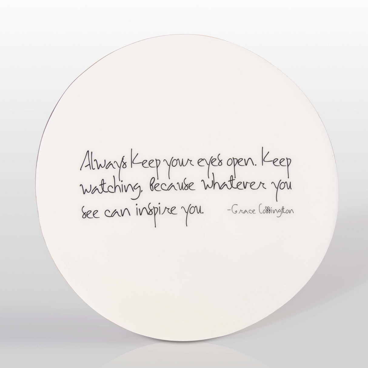 Round white plate with black text on a light gray background