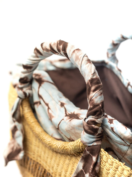 Woven basket with a patterned cloth draped over it on a white background