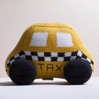 Knitted toy taxi car with checkered pattern on a light background