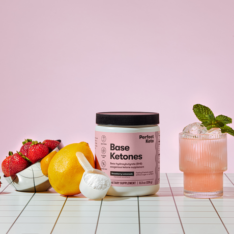 Perfect Keto Base Ketones container with strawberries, lemon, and a cocktail on a pink background