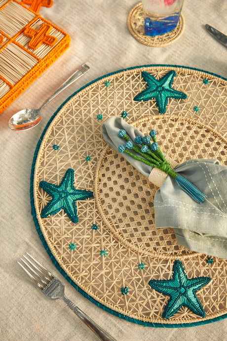 Beige woven placemat with starfish designs on a table setting.