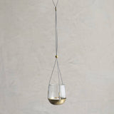 Hanging glass lantern with brass base on a plain background