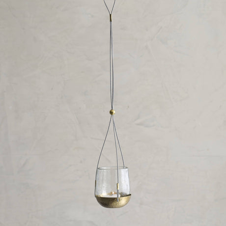 Hanging glass lantern with brass base on a plain background