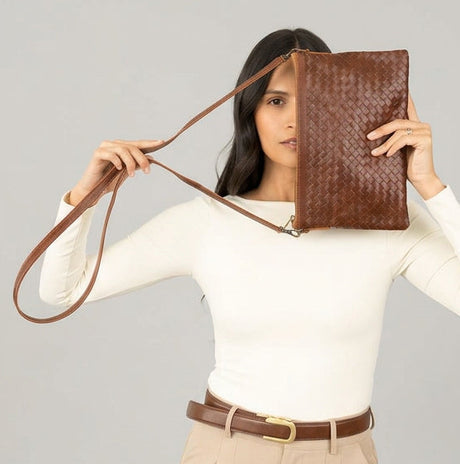 Woman holding a brown woven handbag against a green and beige background
