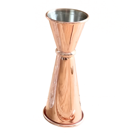 Rose gold jigger and clear glass on a wooden surface