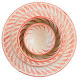 Coral-colored ceramic plates and bowls on a light surface with a spoon and napkin.