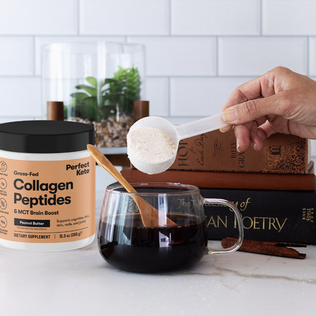 Person adding collagen peptides to a mug of coffee with a container of Perfect Keto Collagen Peptides on a kitchen counter.