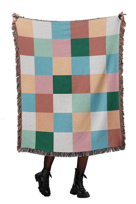 Colorful checkered woven throw blanket with squares in green, blue, pink, and beige.
