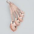 Set of rose gold measuring spoons on a light gray background