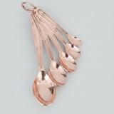 Set of rose gold measuring spoons on a light gray background