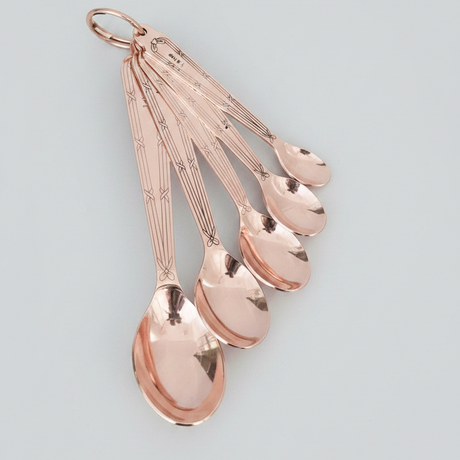 Set of rose gold measuring spoons on a light gray background