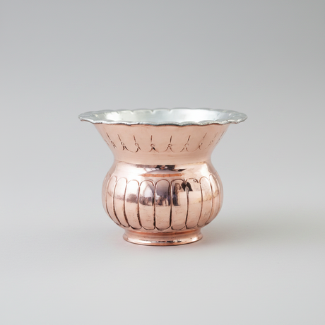 candle in Copper vase with textured design on a white background