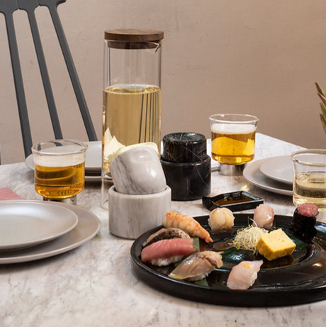 Dinner table with sushi, drinks, and decorative items on a neutral background