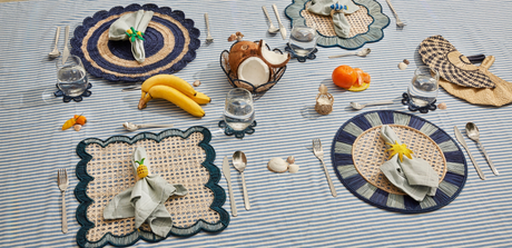 Dining table setting with placemats, cutlery, and decorative items on a striped tablecloth.