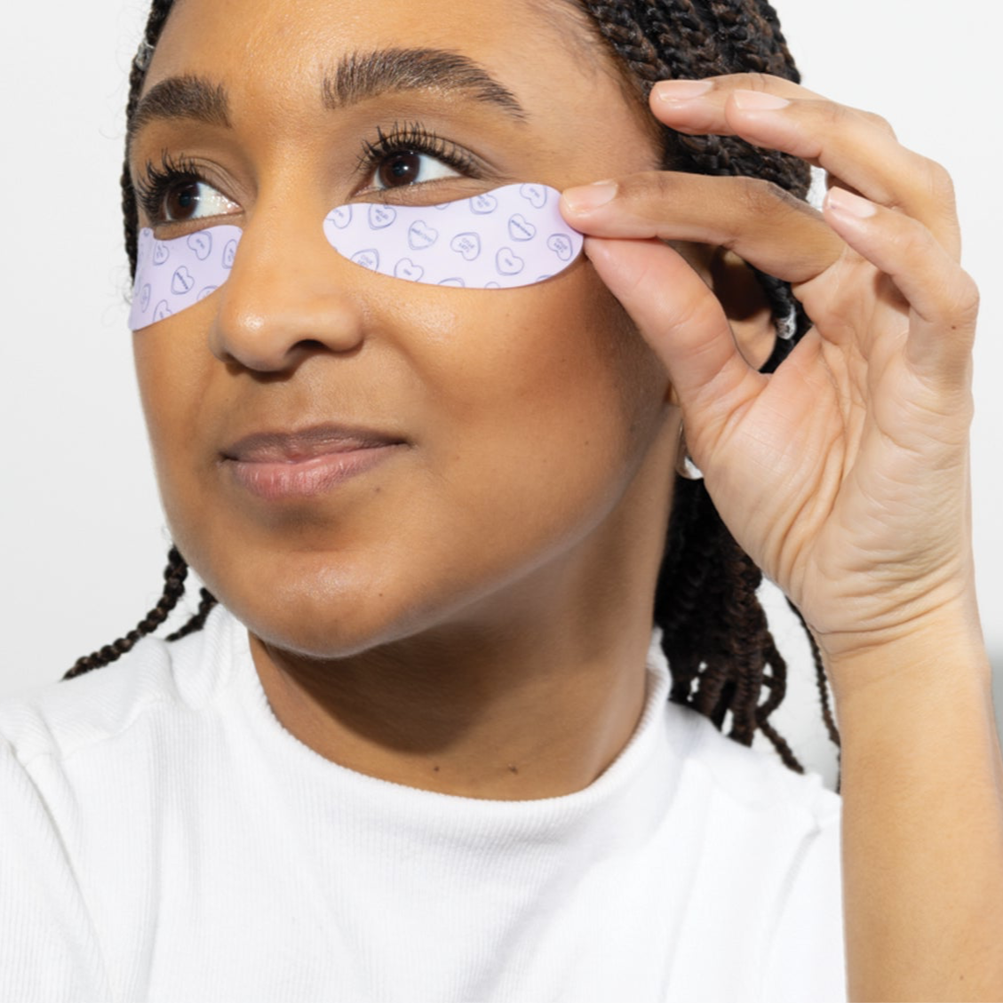 Woman applying eye patches on a white background