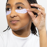 Woman applying eye patches on a white background
