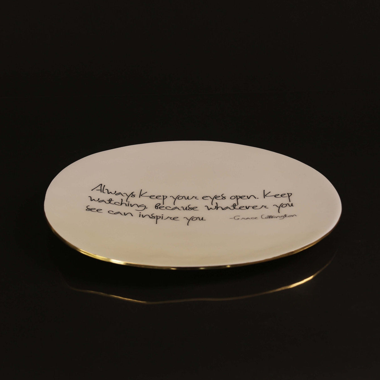 Round plate with a gold rim and engraved text on a black background