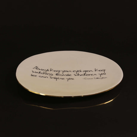 Round plate with a gold rim and engraved text on a black background