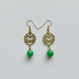 Gold earrings with green beads on a light gray background
