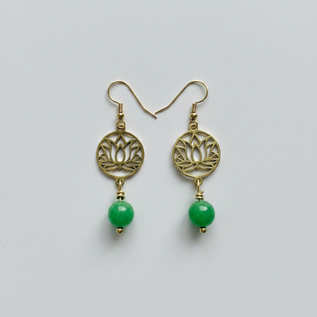 Gold earrings with green beads on a light gray background