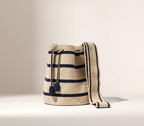 Woven bucket bag with black stripes on a beige background
