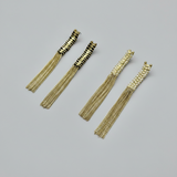 Gold tassel earrings on a gray background