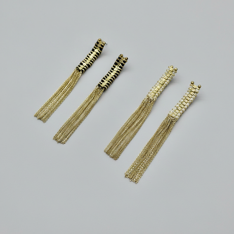 Gold tassel earrings on a gray background