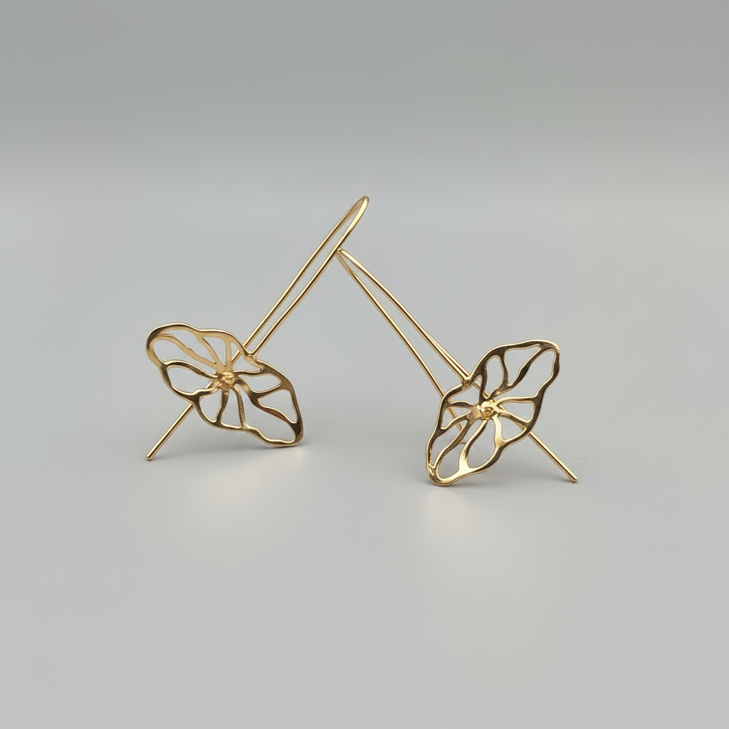 Gold leaf-shaped earrings on a gray background