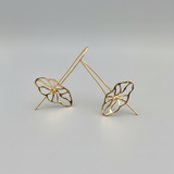 Gold leaf-shaped earrings on a gray background