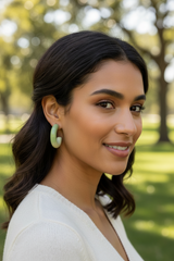 Woman with green earrings smiling outdoors