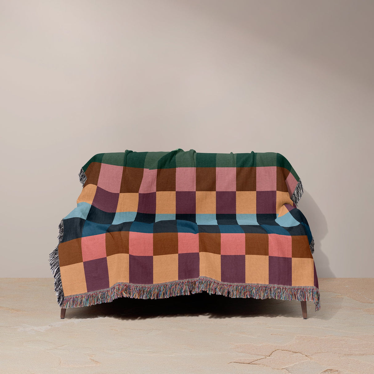 Multicolored checkered blanket draped over a chair against a plain background